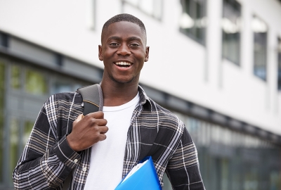 Black student with backpack and notebook smiling