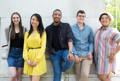 Five Steinhardt students leaning against the Washington Square Arch