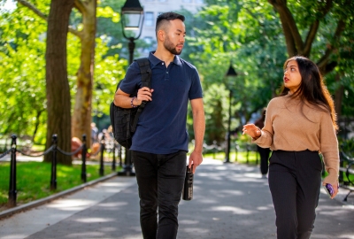 Male and Female student walking through Washington Square Park Conversing