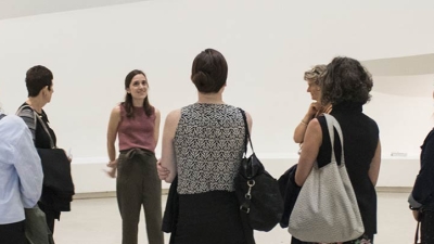 People gathered in around another person in a gallery