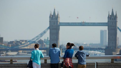 Four people standing facing the London Bridge.
