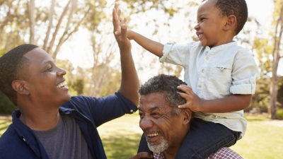 Child riding on an adult's shoulders and high fiving another adult