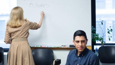 Professor Leanna Stiefel writing on a whiteboard