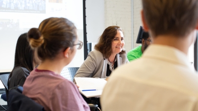Professor Carol Anne Spreen sitting with NYU students