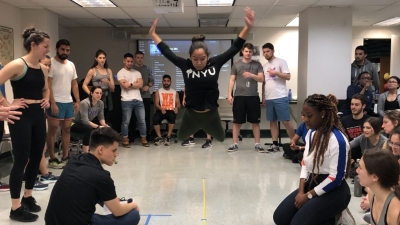 A student jumping in the air with her arms raised.
