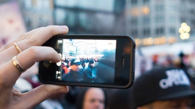 Someone holding up a cellphone filming activity in NYC