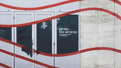 A wall with red squiggles painted over it and a doorway reading "Entree Des Artistes"
