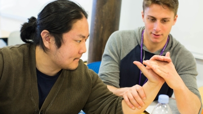 One student practicing a wrist and hand assessment on another student.