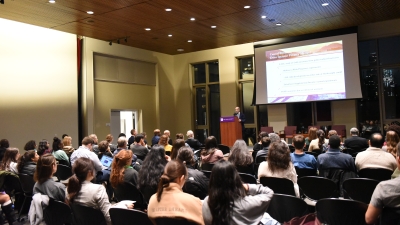 An audience watches Benard Dreyer give a presentation