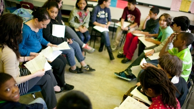 students discussing paperwork with a teacher