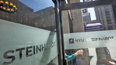 Students walking out of an open door labelled with NYU Steinhardt