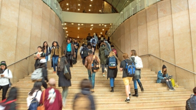 Abusy scene of many students walking up and down the main stairs in Kimmel Center for University Life