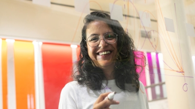 An international grad student writing on a clear whiteboard
