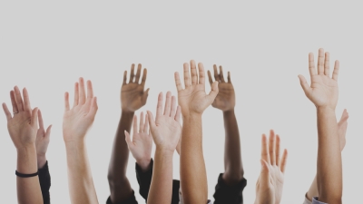 Raised hands of various skin shades.