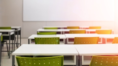An empty classroom with a white board up front