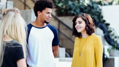 Four teenagers stand outside in a semi-circle talking and laughing
