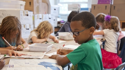 A photo of an elementary school classroom with six children reading and writing