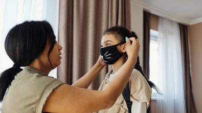 A mother puts a mask on her young daugther
