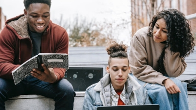 A group of racial diverse students sit together happily studying