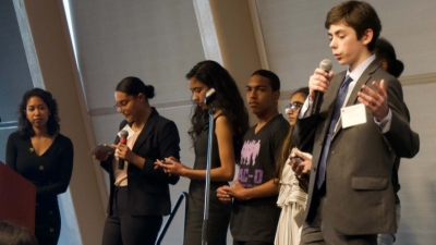 Youth stand on stage, presenting about educational disproportionality