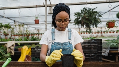 A woman in a greenhouse working with potting soil.