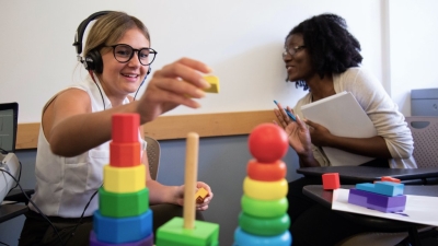 Students using audiology equipment and rainbow colored blocks.