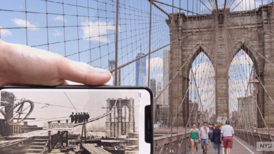 Brooklyn Bridge behind a Mobile phone with historical photo of the bridge