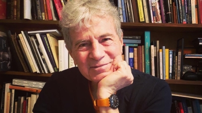 man smiling in front of bookshelf 