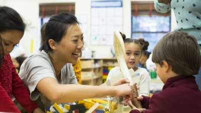 An NYU student works in a classroom with young children as they play with toys