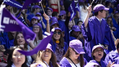 NYU Steinhardt graduates at yankee stadium waving flags