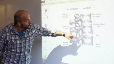faculty member pointing to a projection screen of a closeup on the spine