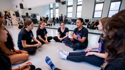 NYU dance class with students sitting on the floor in a circle