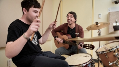 Music Therapy faculty working with student on the drums