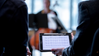 two individuals looking at sheet music on an iPad