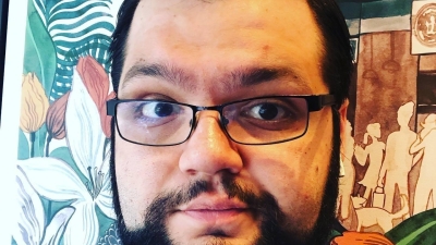 Photo of Mike Burgos; Purple collared shirt and black framed glasses