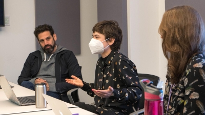 Student wearing a mask presenting to a faculty member and other students