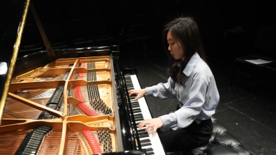 Woman playing grand piano with a view of the inside of the piano