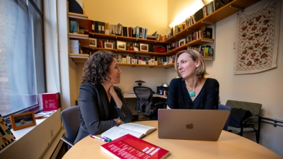Professor Dana Burde smiling and Professor Heddy Lahmann having a meeting in Dana's office