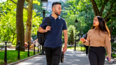 Male and Female student walking through Washington Square Park Conversing