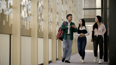 3 students walking through the halls of Bobst Library