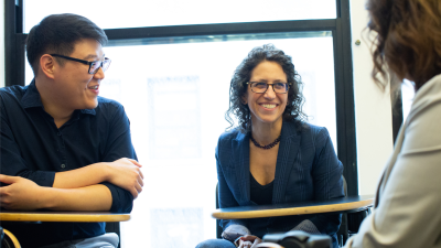 Professor Dana Burde smiling and in conversation with other faculty