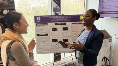 Woman presents her research poster to an event attendee