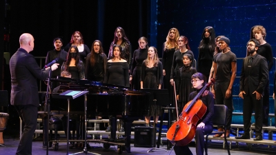 Chorale students performing on stage with a cello player