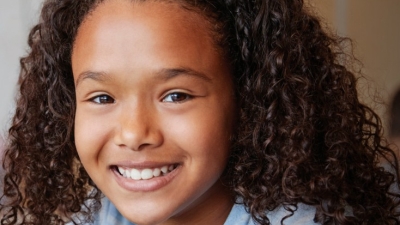 Image captures a closeup shot of a child seated in her classroom. Thi
