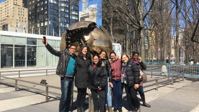 A group of IPA students, faculty, and NYU faculty in front of a sculpture at the United Nations