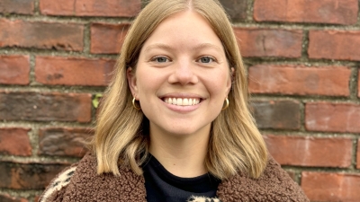 woman smiling on front of a brick wall 