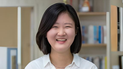 Professional headshot of Miri, smiling with arms folder comfortably in front of them