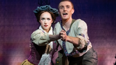Performers on stage dancing while looking into the camera