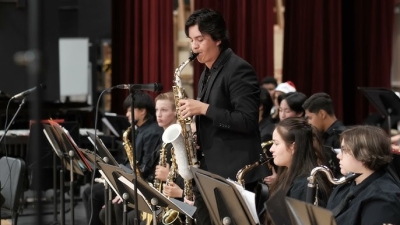 Saxophonist standing up playing solo in sax orchestra