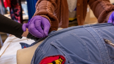 Students zip a suit on a child mannequin